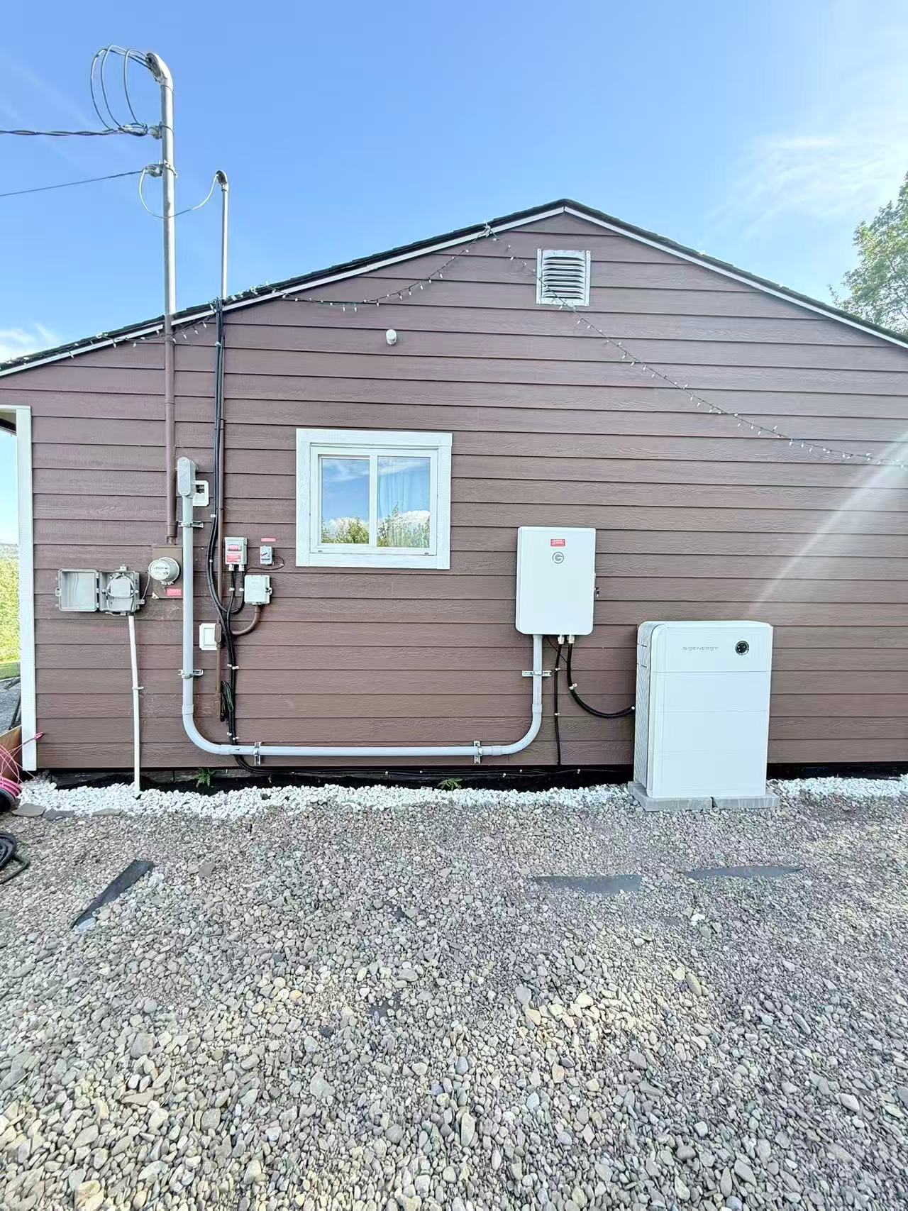 White battery storage cabinet installed beside the brown exterior wall of a house